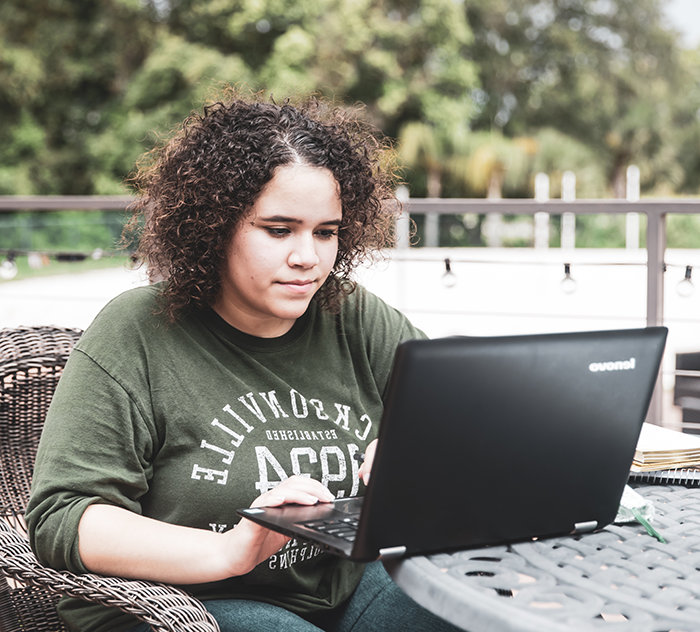 Student on the JU green browsing on her laptop.