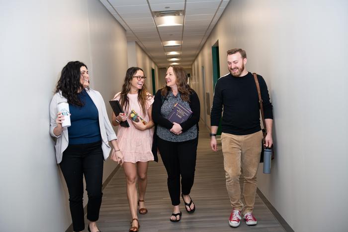 四名学生微笑着走在杰克逊维尔大学大楼的走廊上.