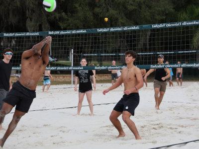 A group of young people playing beach volleyball