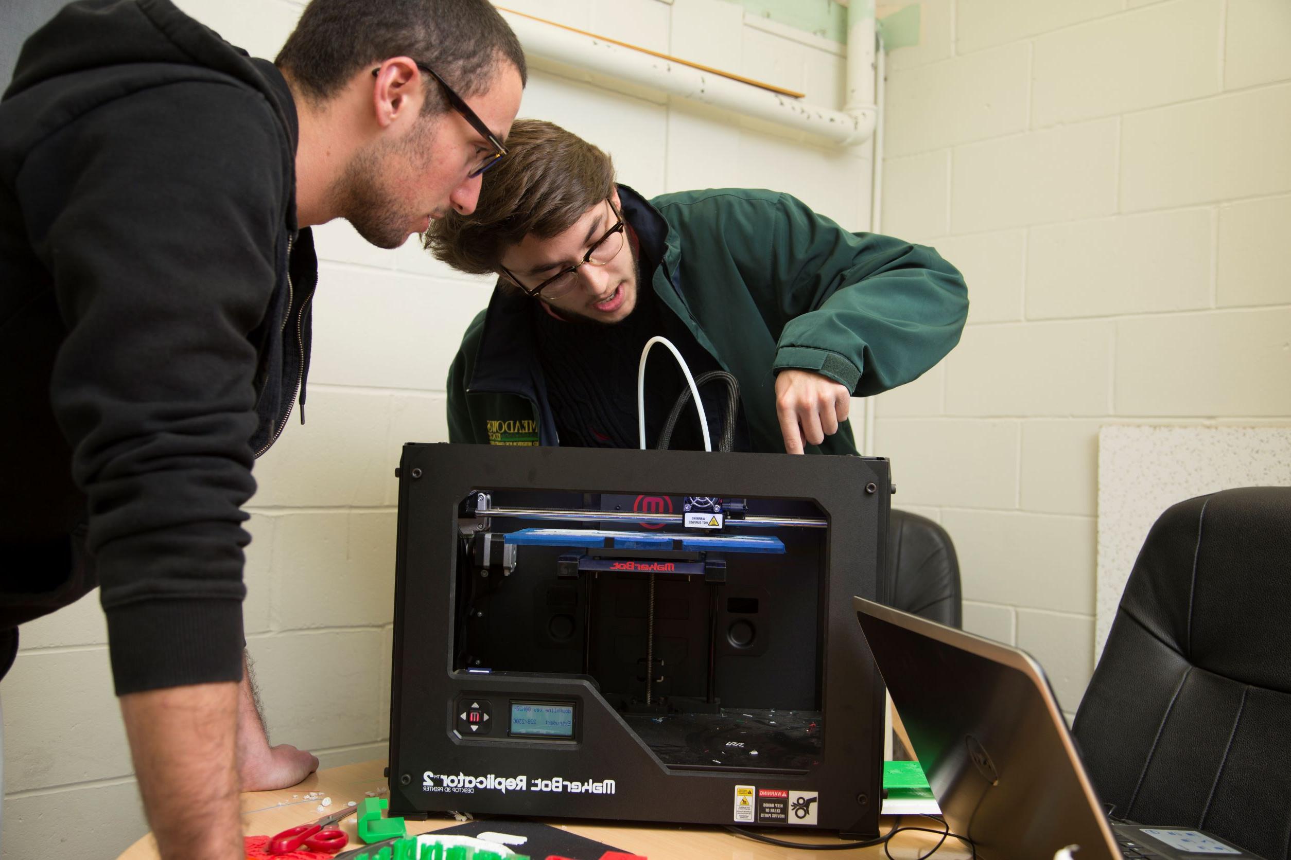 两个工程专业的学生正在研究一台复制机.