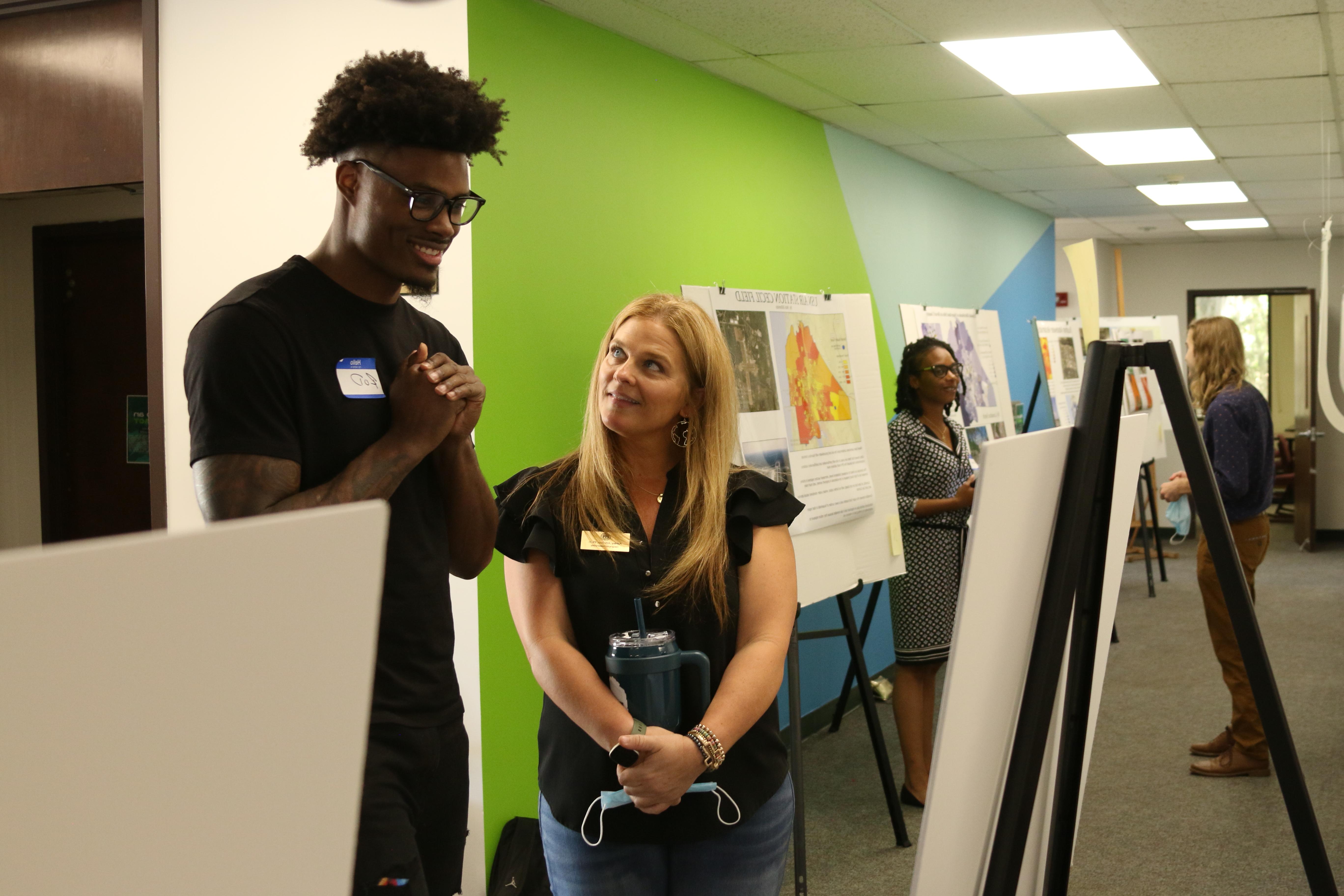 Dr. 阿什利·约翰逊和一名男学生在一面绿蓝相间的彩色墙前一起看地图.