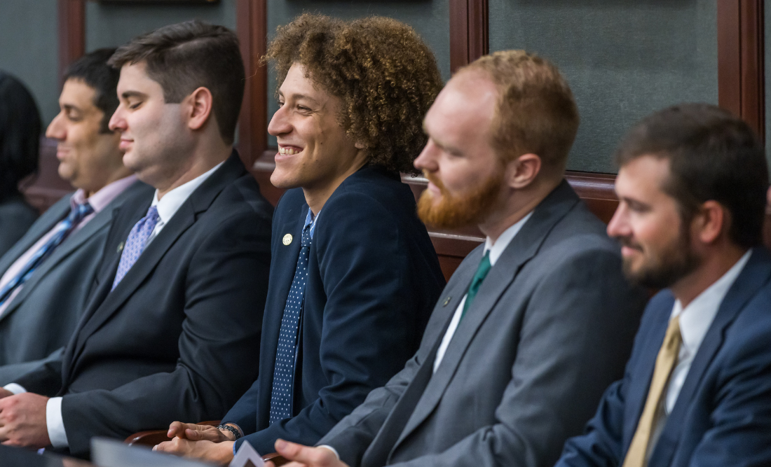 一群男学生坐在法庭的陪审席上，面带微笑. 